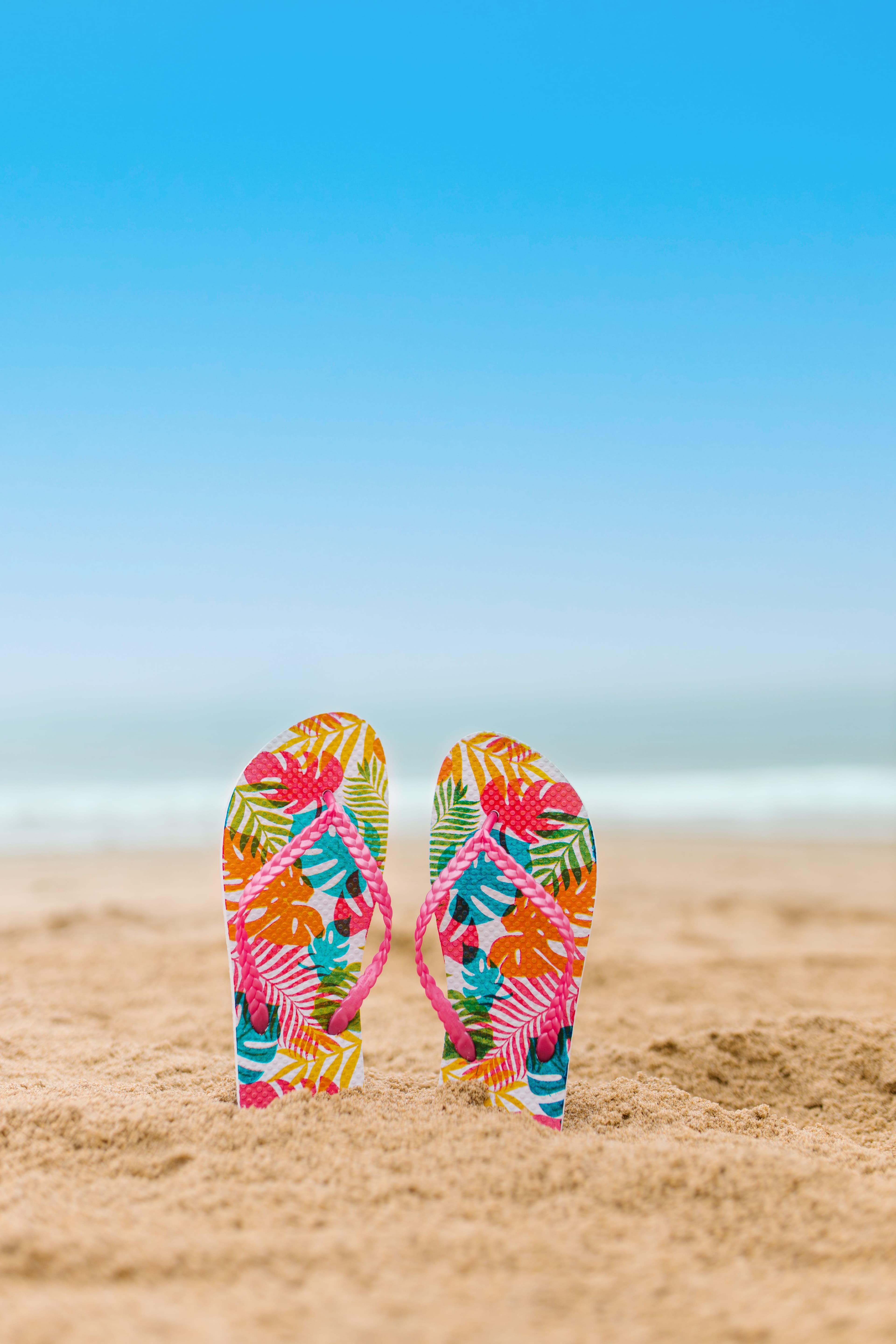 Photo de 2 tongs plantées dans le sable sur une plage pour représenter les vacances